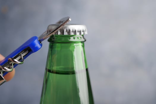 Opening a green glass bottle with a bottle opener photo