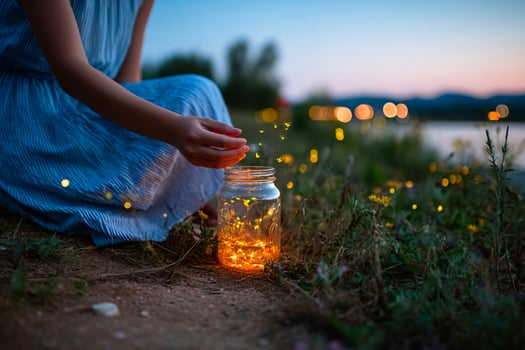 Girl lets glowing fireflies fly from a jar, capturing summer magic and warm night memories photo
