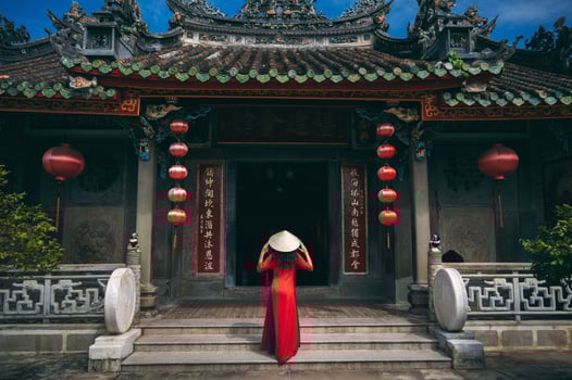 A woman in a traditional Vietnamese costume and a conical hat on the background of an ancient building in Hoi An, Vietnam. photo