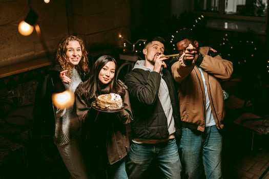 Friends celebrate a birthday at a cozy cafe during the evening with cake and cheerful laughter photo