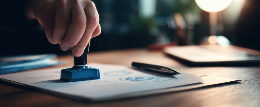 The hand using a blue stamp on an official document on a wooden desk photo