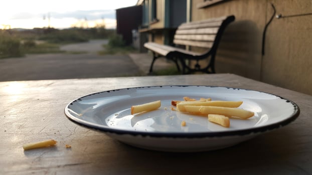 A plate of french fries on a table with a bench and landscape in the background at golden hour light photo