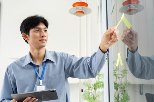 Businessman Organizing Ideas. Professional placing sticky notes on a glass wall. photo