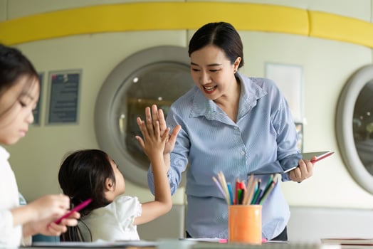 Back to School. Teacher celebrating a young girl's achievement in a vibrant classroom. photo