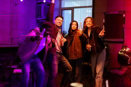 Friends celebrating joyfully at a vibrant nighttime gathering with drinks in a festive setting photo