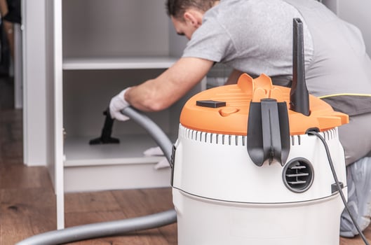 Cleaning a Cupboard With a Vacuum in a Modern Kitchen During Daylight Hours photo