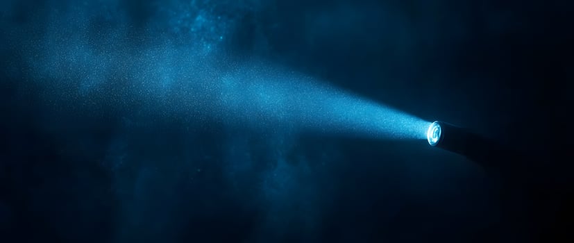 A bright beam of blue light radiates from a high powered spotlight in darkness photo