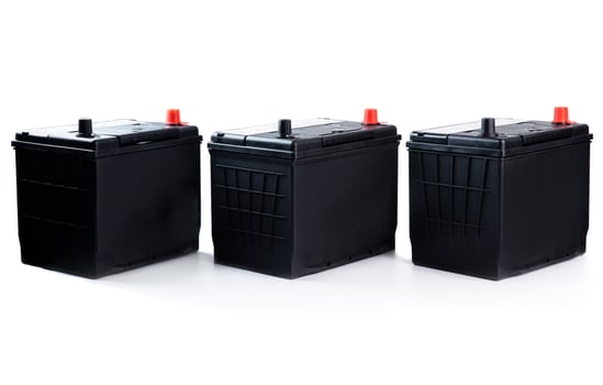 Three identical black car batteries in a row on white background. Isolated automotive parts for passenger vehicle repair, catalog, or store use. photo