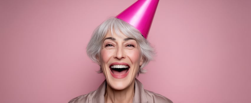 The joyful elderly woman celebrating with a vibrant pink party hat. photo