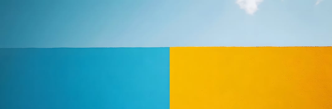 Bright blue sky meets vibrant yellow textured wall creating a modern abstract color block photo