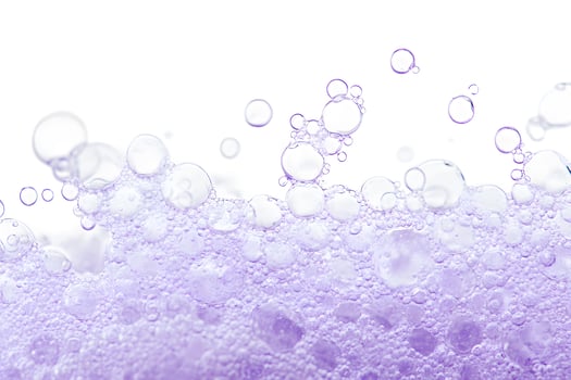 Close up reveals vibrant purple soap bubbles against a crisp, clean white backdrop photo