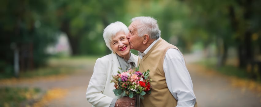 The elderly couple sharing a loving kiss in a scenic park setting photo