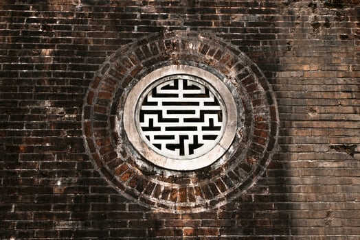 Beautifully Crafted Round Window Featuring Intricate Lattice Design Set in a Traditional Brick Wall. photo