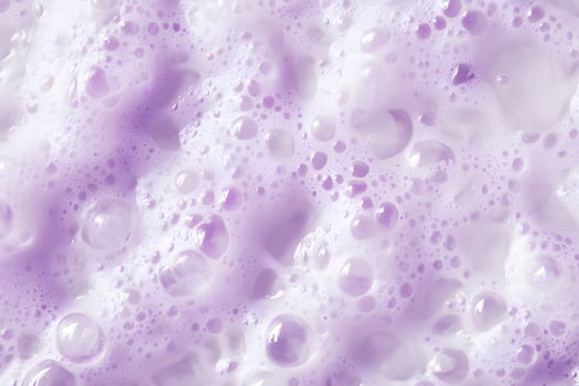 Delicate lilactinted bubbles and foam form a visually captivating, textured surface in closeup photo