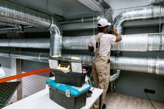 HVAC technician installing ductwork in a modern commercial space during daylight hours photo
