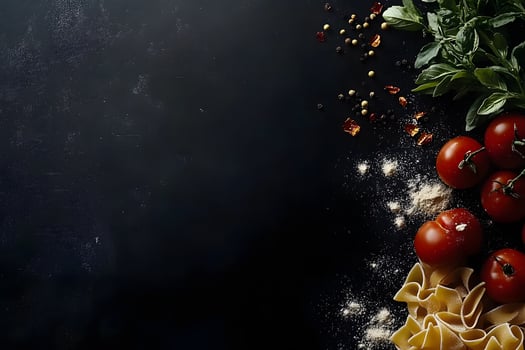 Fresh basil, tomatoes, pasta, and assorted peppercorns compose the elements along dark stone photo
