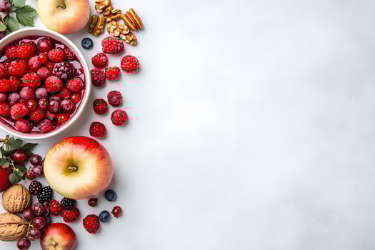 Fresh ripe raspberries in bowl beside whole apples and assorted nuts create a colorful arrangement photo