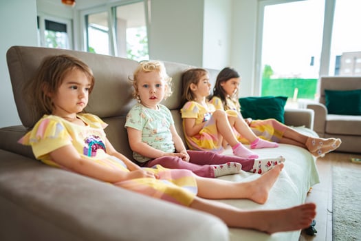 Four children relax on a cozy sofa in bright living room photo