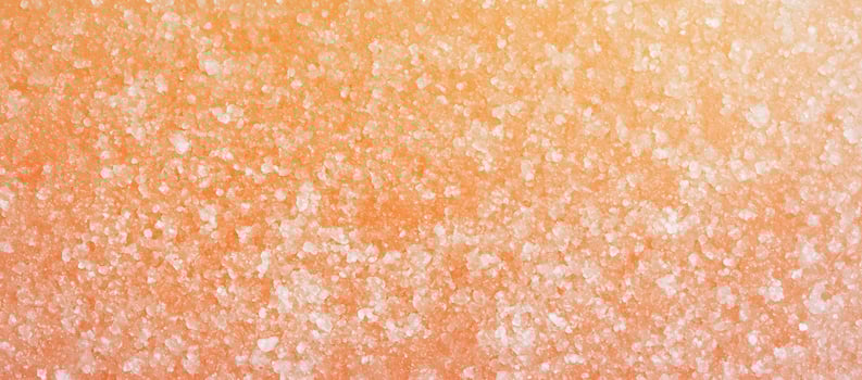 Peachcolored salt crystals are scattered across the entire frame, creating a textured surface photo