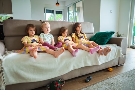 Four children relax on a couch in colorful attire photo