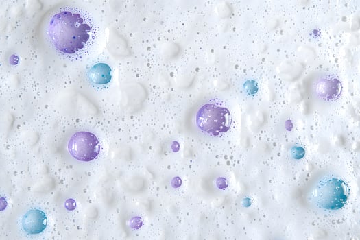 Shiny pastel spheres float among light white foam and tiny water droplets create texture photo
