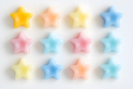 Twelve pastel star shaped candies are arranged in a grid pattern on white photo