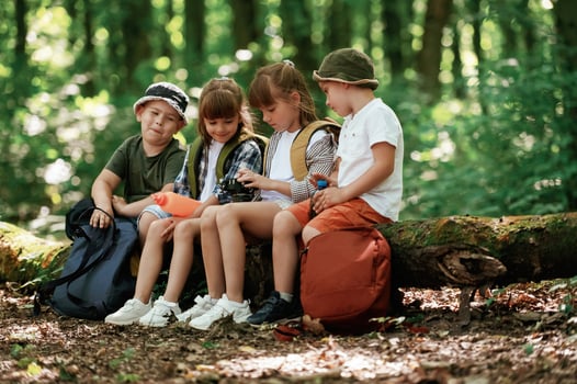 Sitting ,with camera and water bottle. Kids in forest at summer daytime together photo