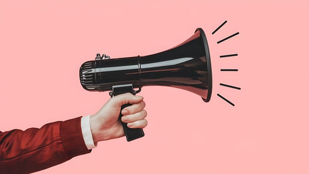 Hand holding megaphone in pink background, communication concept to alert photo