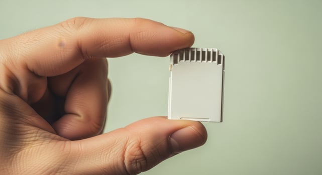 Human hand holding a white SD card, a compact digital memory storage device for modern technology. photo