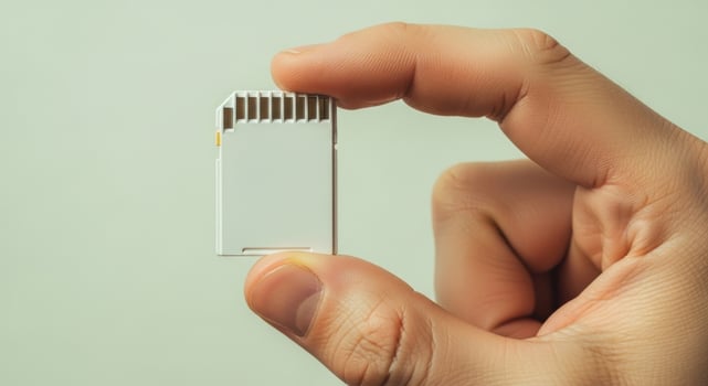 Person hand holding a white SD memory card for data storage and digital information. photo