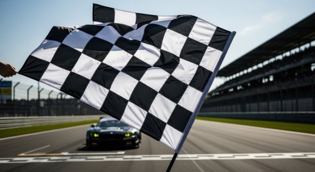 Checkered flag waving at a race track with a car approaching the finish line, symbolizing victory photo