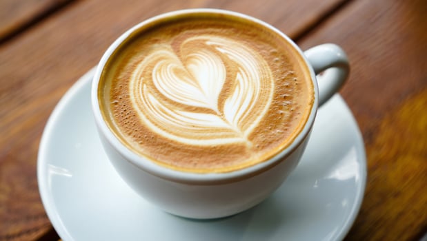 Coffee Background Aromatic Latte Coffee with Heart Design Close Up View in White Cup on Wooden Table photo