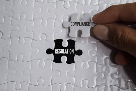 Hand holding piece of jigsaw puzzle with word Compliance regulation. Business and finance concept photo