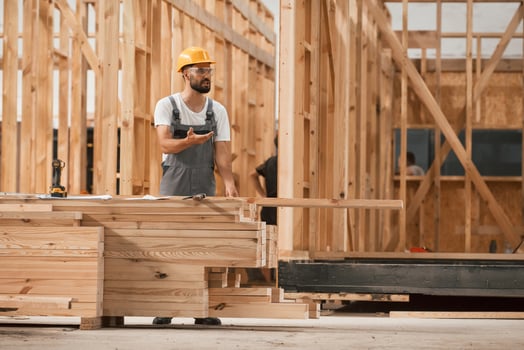 Walking,, holding ,,plank. Industrial worker in wooden warehouse photo