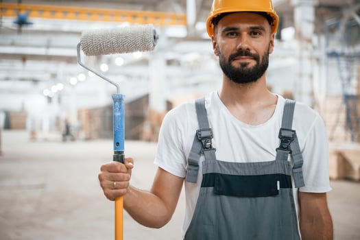 With, brush for coloring. Industrial worker in wooden warehouse photo
