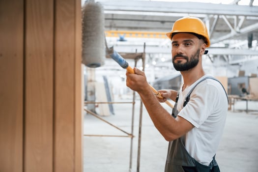 With brush, for coloring. Industrial worker in wooden warehouse photo