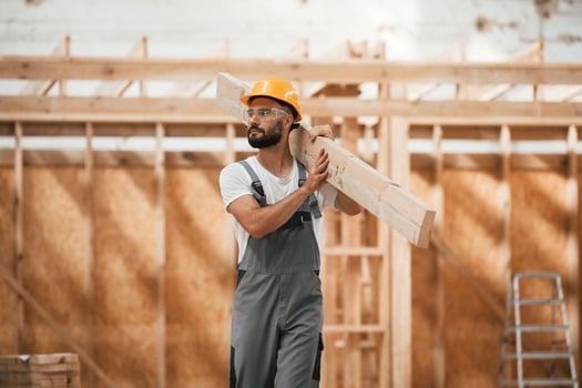 Walking, holding, plank. Industrial worker in wooden warehouse photo