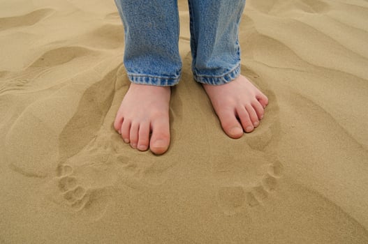 a person standing in the sand with their feet in the sand photo