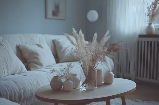 Soft light bathes a living room adorned with neutral tones and dried flower arrangements. photo