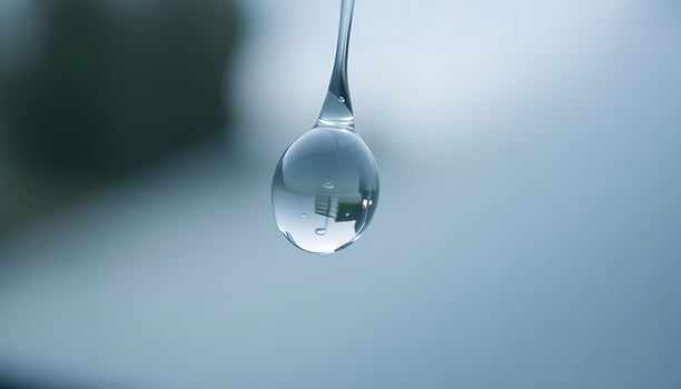 A drop of water hangs from a spoon photo