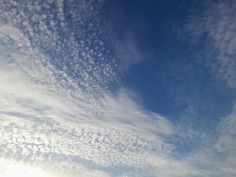 A calm sky filled with soft, scattered clouds, creating a serene and peaceful atmosphere under the gentle blue photo