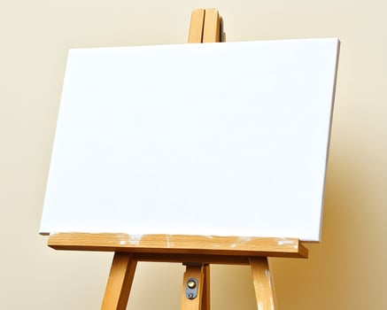 Blank canvas on an easel against a beige wall. photo