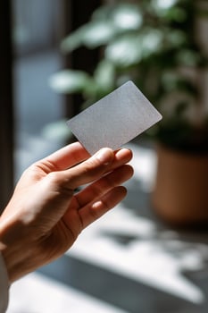A person holding a credit card in front of a plant photo