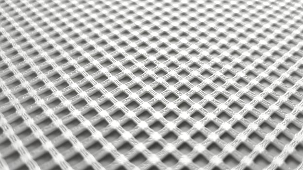 Close up perspective of a net like fabric with a white pattern against a neutral gray background photo