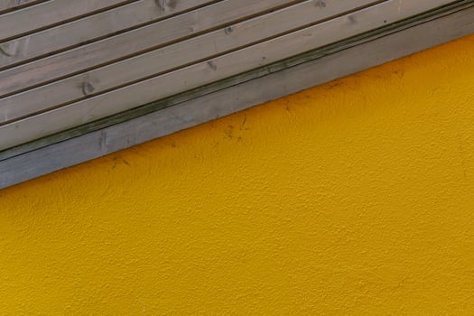 Yellow plastered wall. Wooden boards diagonally. photo