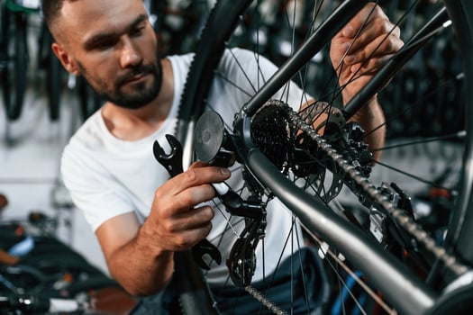 Checking, the ,wheel and brake system. Repair man in bicycle shop, working in store photo