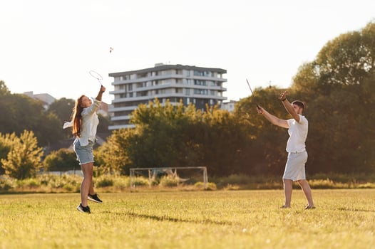 Side, view. Man with woman are playing ,,,badminton on the field photo