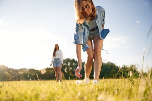 Picking ,up the fallen ,shuttlecock. Two women are having fun, with badminton rackets, on the field photo