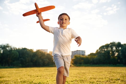 Happy boy ,is, running with toy plane on the summer field photo
