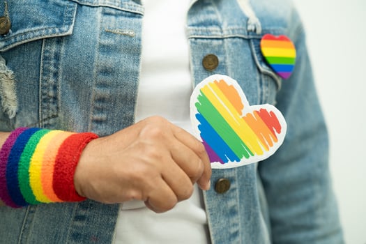 Asian lady wearing rainbow flag wristbands and hold red heart, symbol of LGBT pride month photo